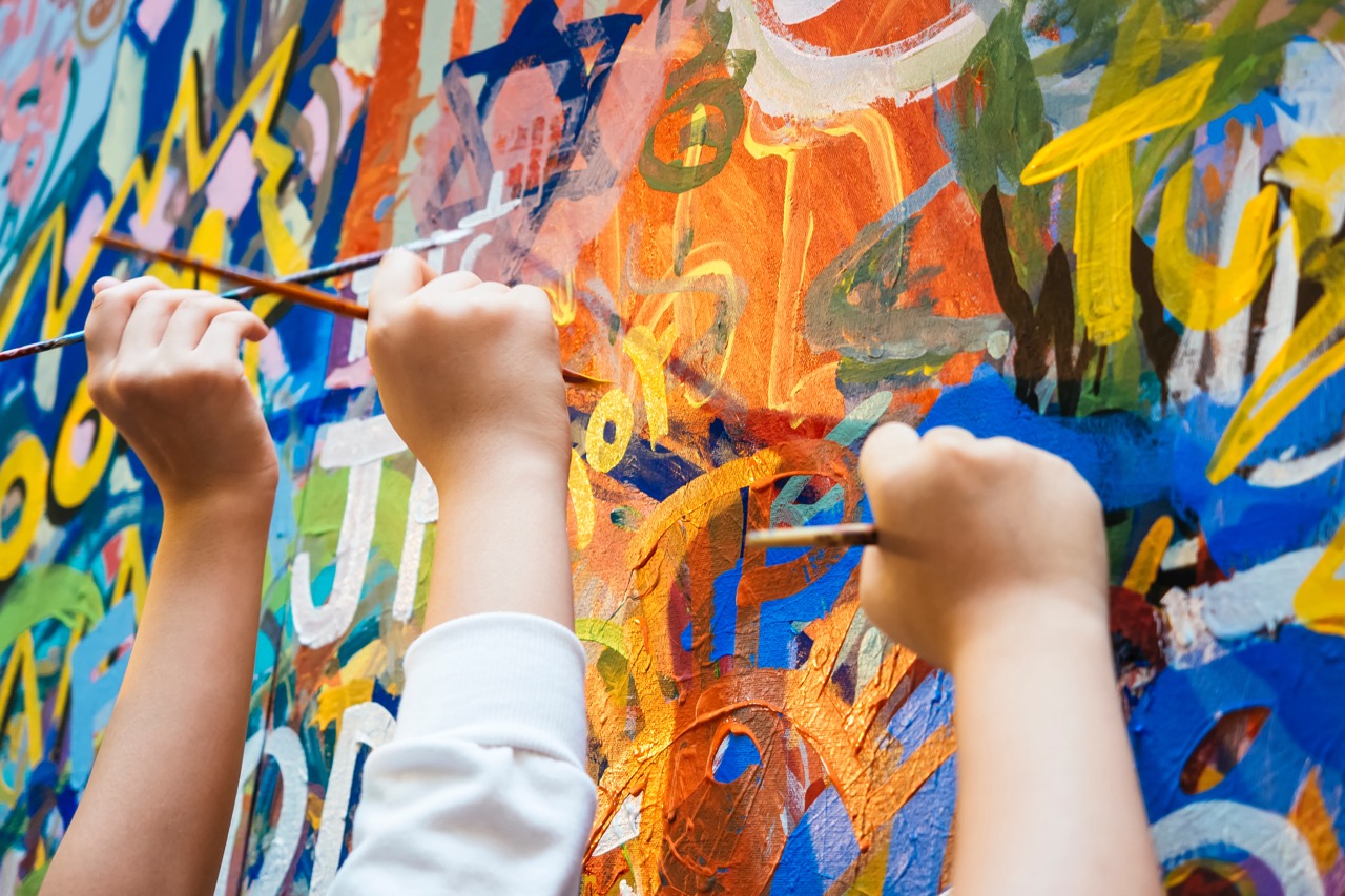 Kids hands painting colorful art on a wall